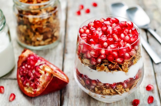 un yaourt avec de la grenade et du muesli