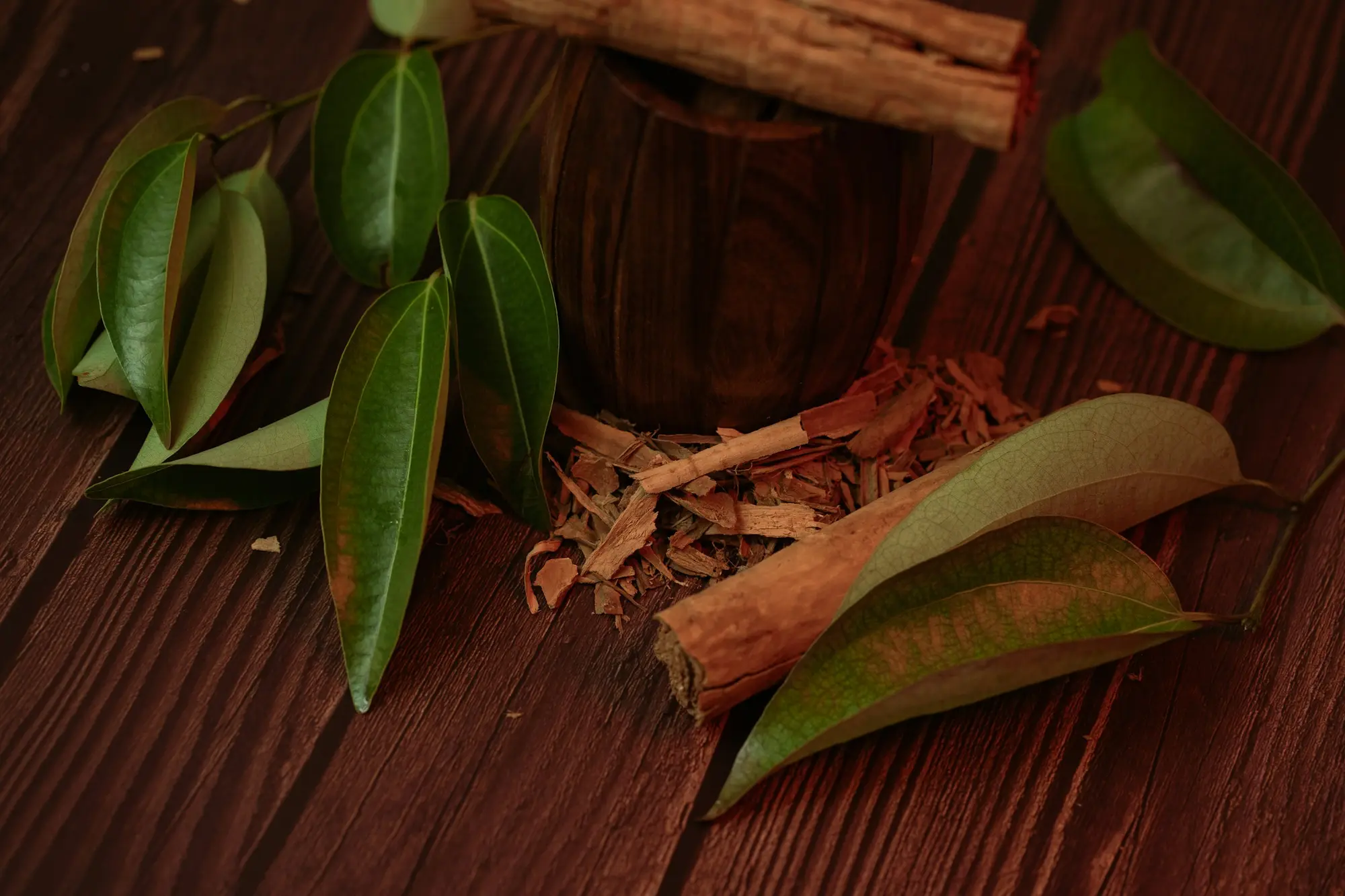 Palitos de canela y hojas sobre una superficie de madera